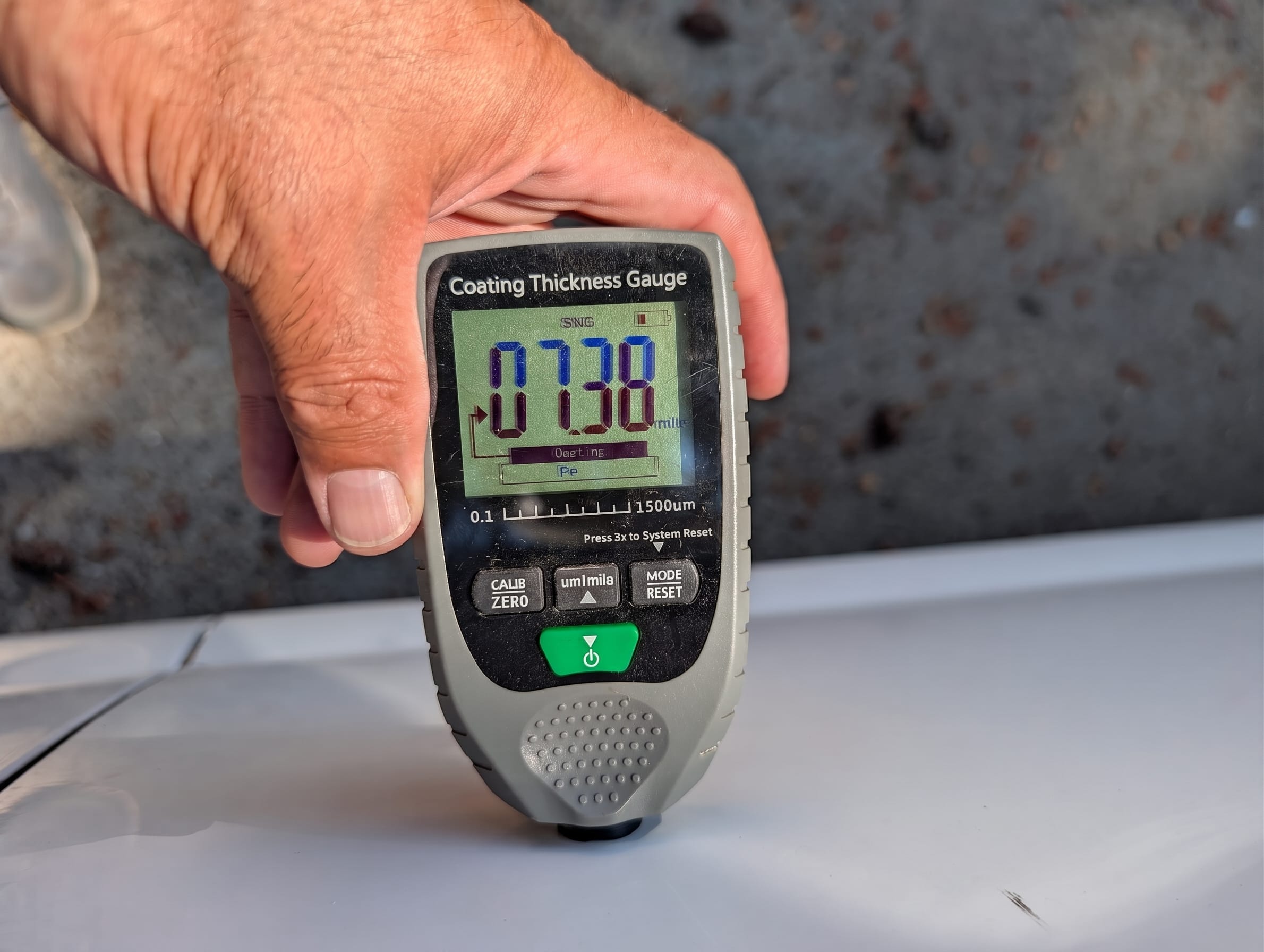 Digital paint depth gauge checking bondo during classic car inspection