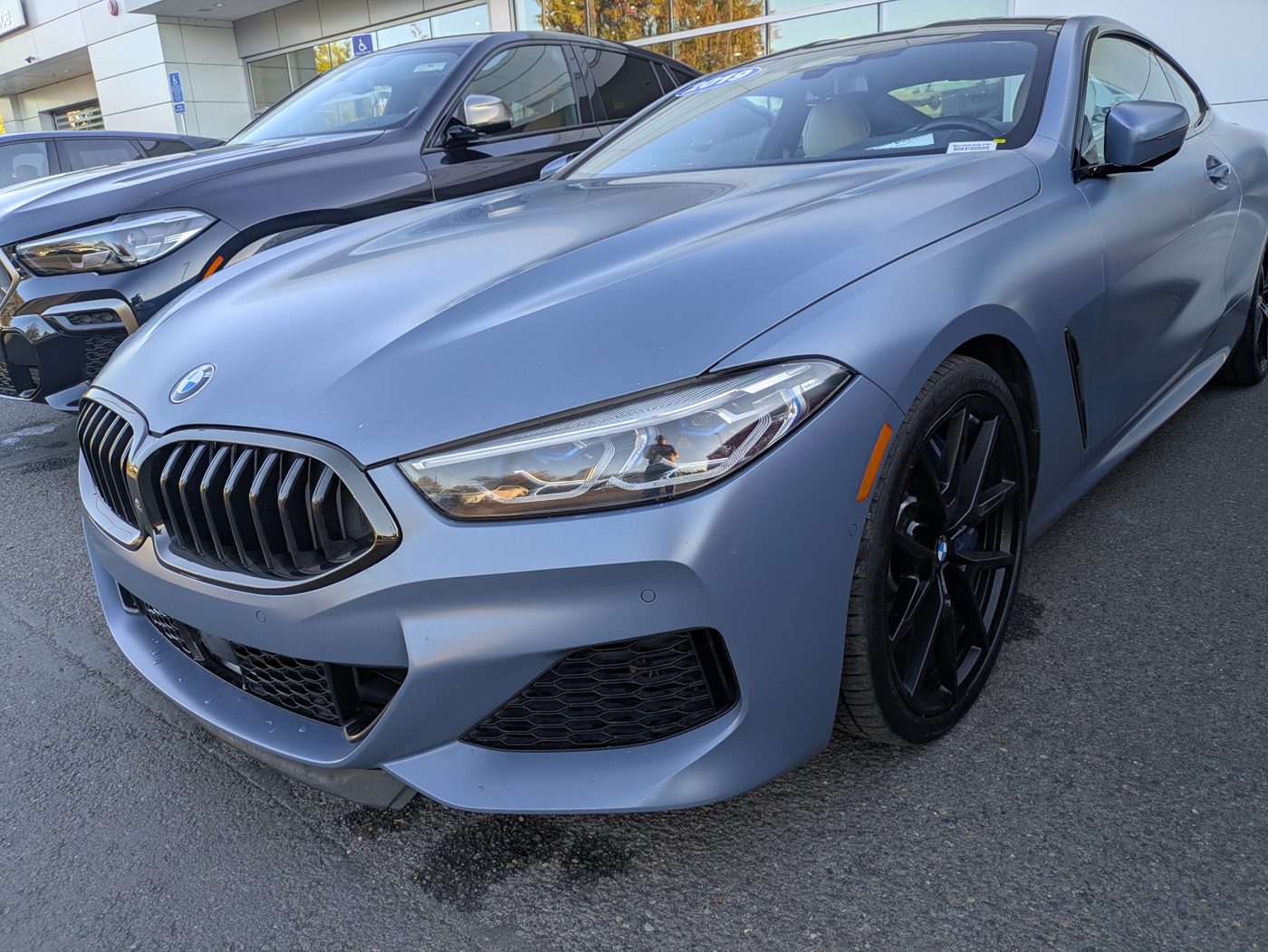 Matte blue BMW M850i coupe photographed from the front three-quarter during an exotic car inspection