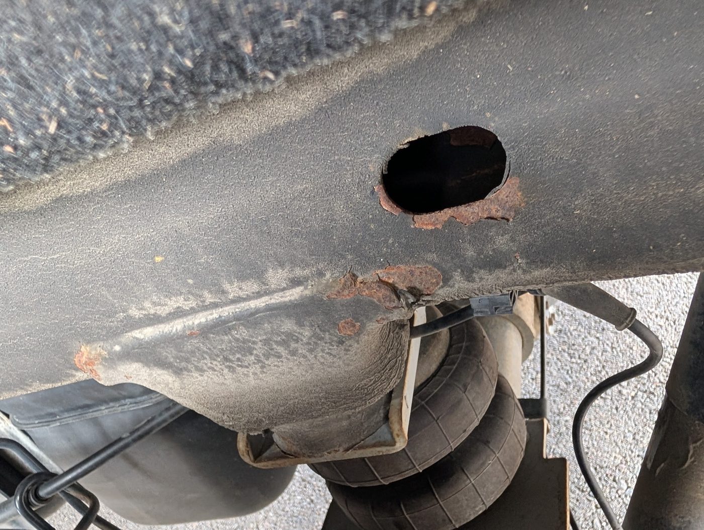 Close-up frame rail inspection, checking for rust-through and structural damage