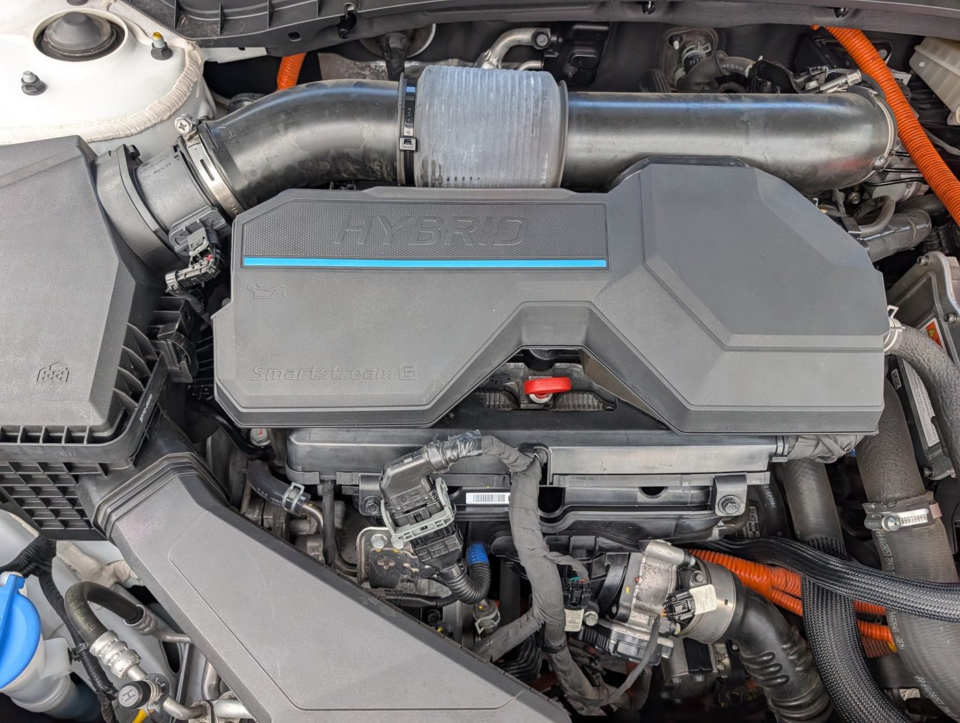 Hybrid engine bay with orange high-voltage cabling on a Hyundai Tucson Hybrid