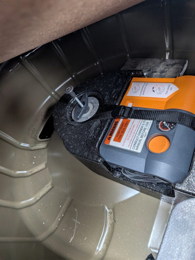 Spare tire inflator kit checked in the trunk during a pre-trip vehicle inspection